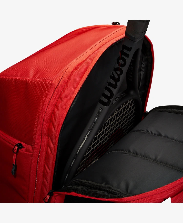 The Wilson Super Tour Backpack in red with a tennis racket inside for display purposes which is available for sale at GSM Sports.