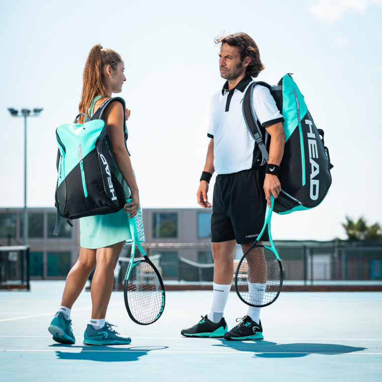  The Head Tour Team 12 Racket Monstercombi Tennis Bag in mint and black colour on a tennis court which is available for sale at GSM Sports.